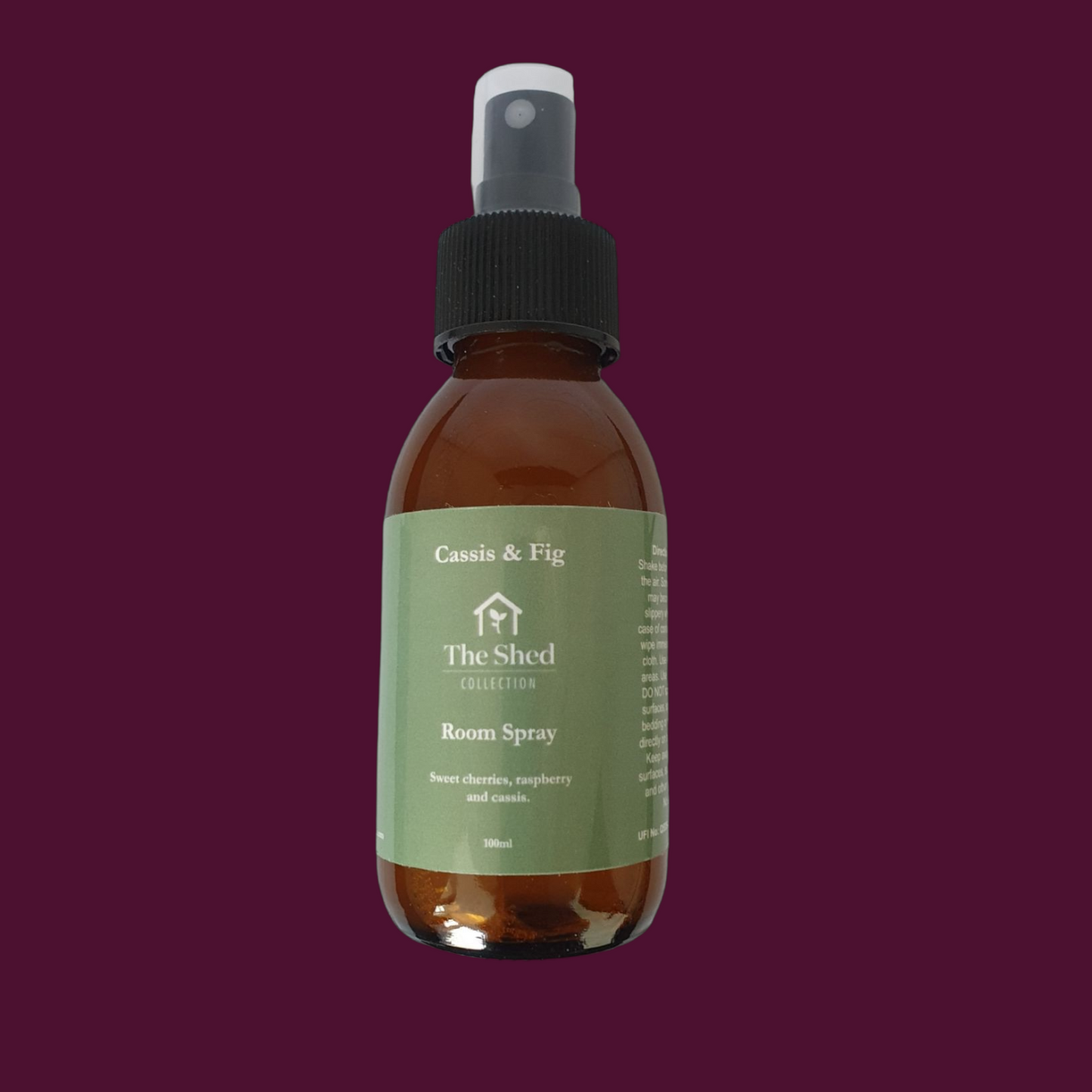 Picture shows a vegan friendly Cassis & Fig room spray from The Shed Collection in a brown glass bottle with black spray lid against a cassis coloured background.