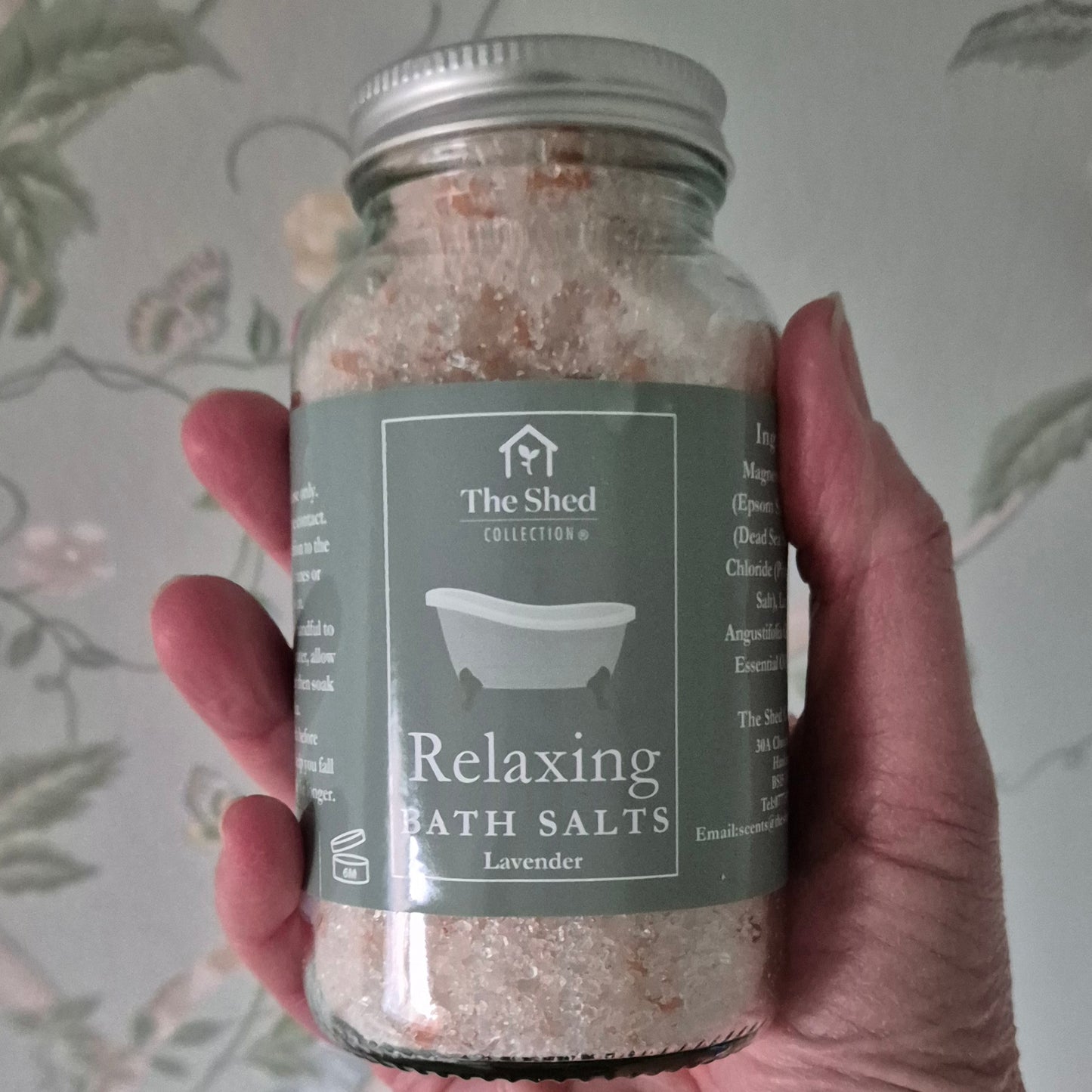 Jar of relaxing lavender bath salts held by a hand with a floral-patterned background