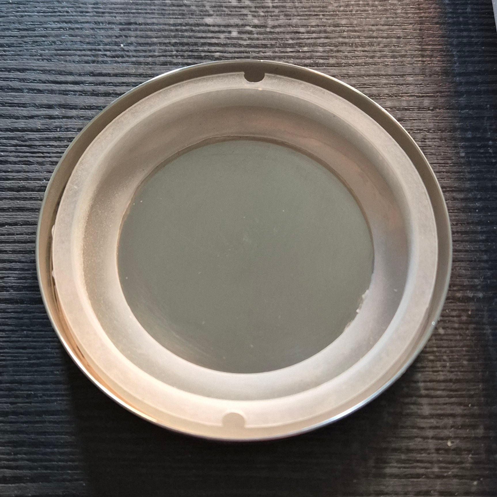 Roundcandle lid inside showing seal on a textured dark surface