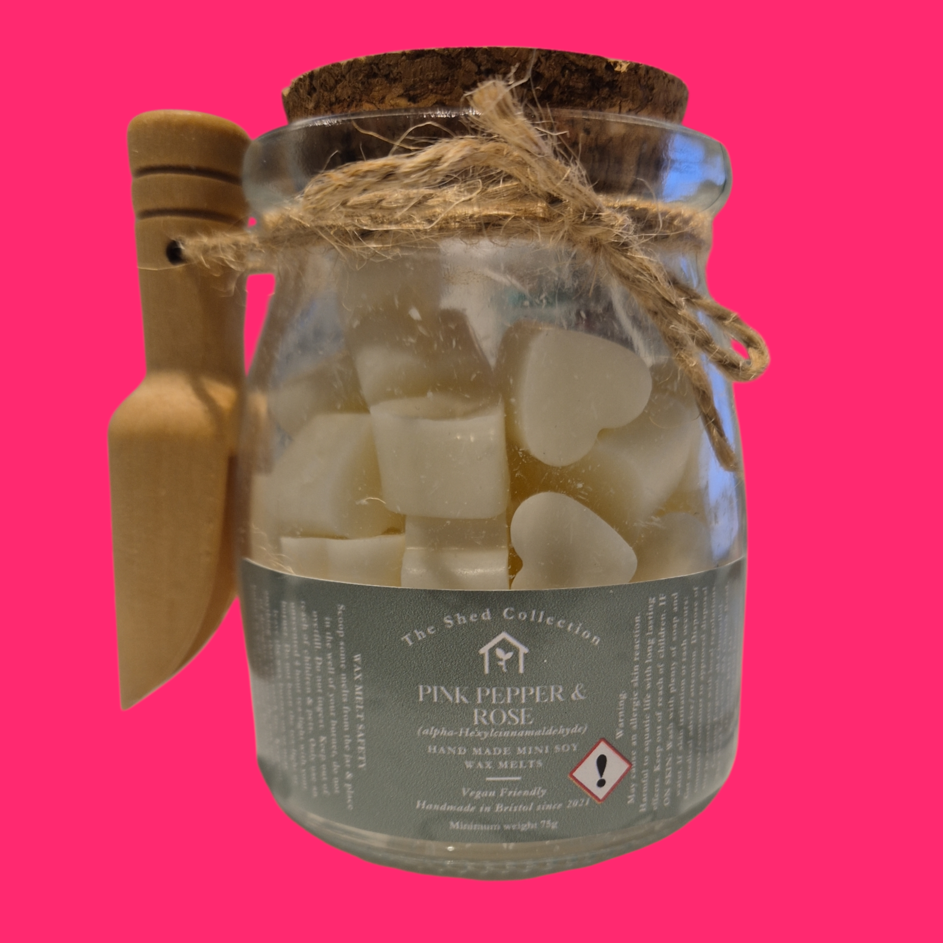 Jar of heart-shaped wax melts with a cork lid on a pink background