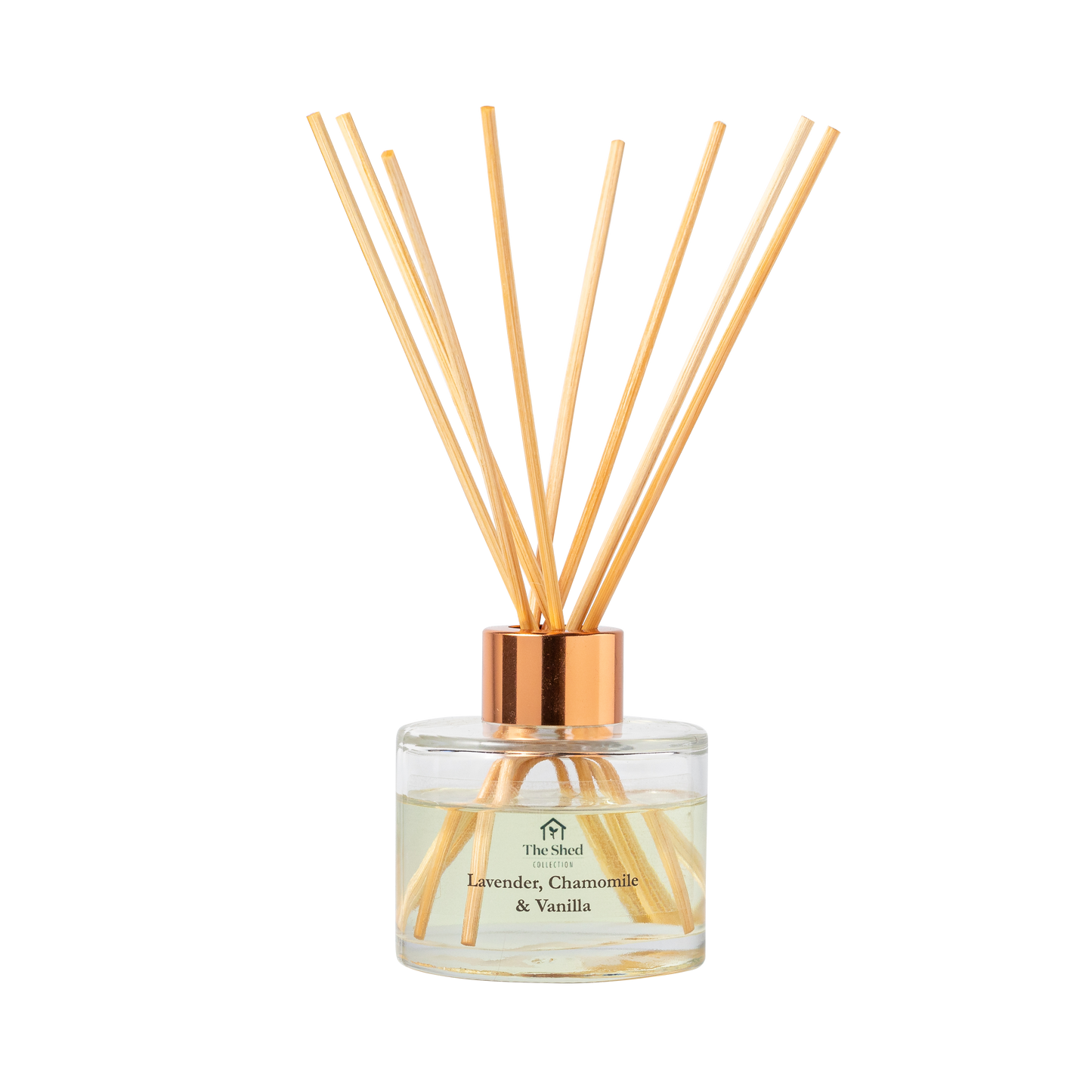A reed diffuser bottle with a clear glass base, pale yellow liquid, cap and natural reeds, labeled 'The Shed Collection Lavender, Chamomile & Vanilla'.