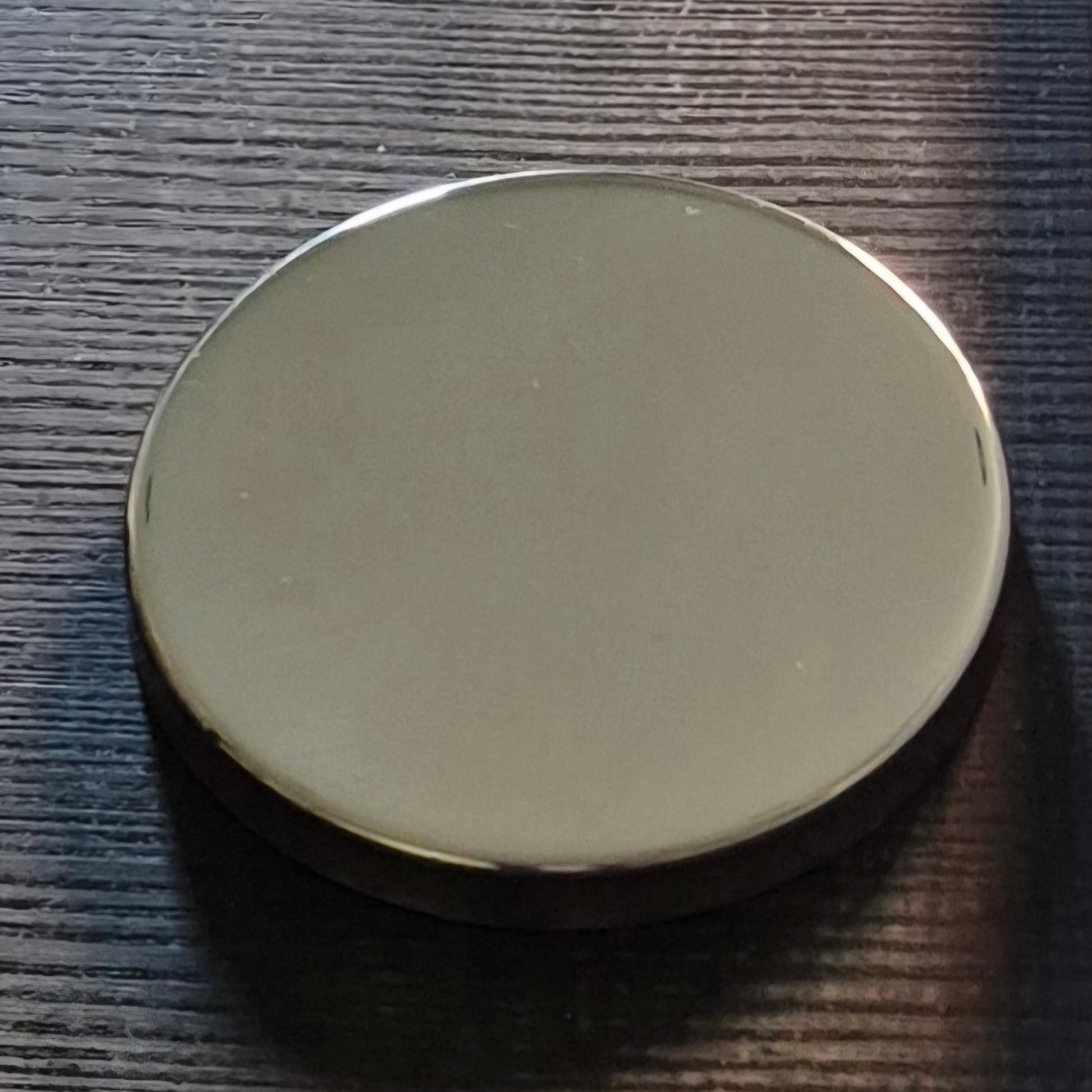 Round silver candle lid on a textured dark surface