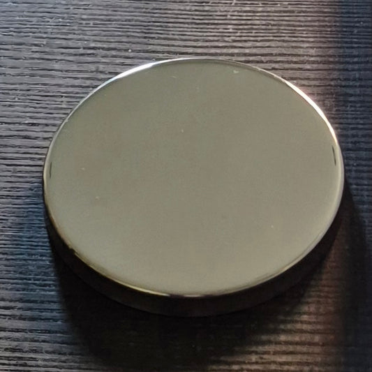 Round silver candle lid on a textured dark surface