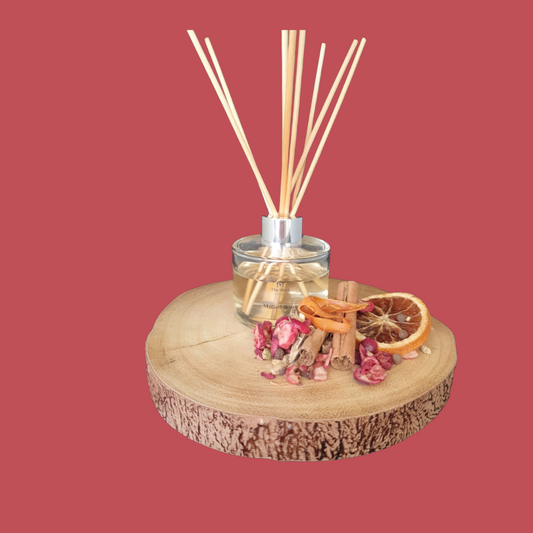 Diffuser with wooden sticks and decorative elements on a wooden base against a red background