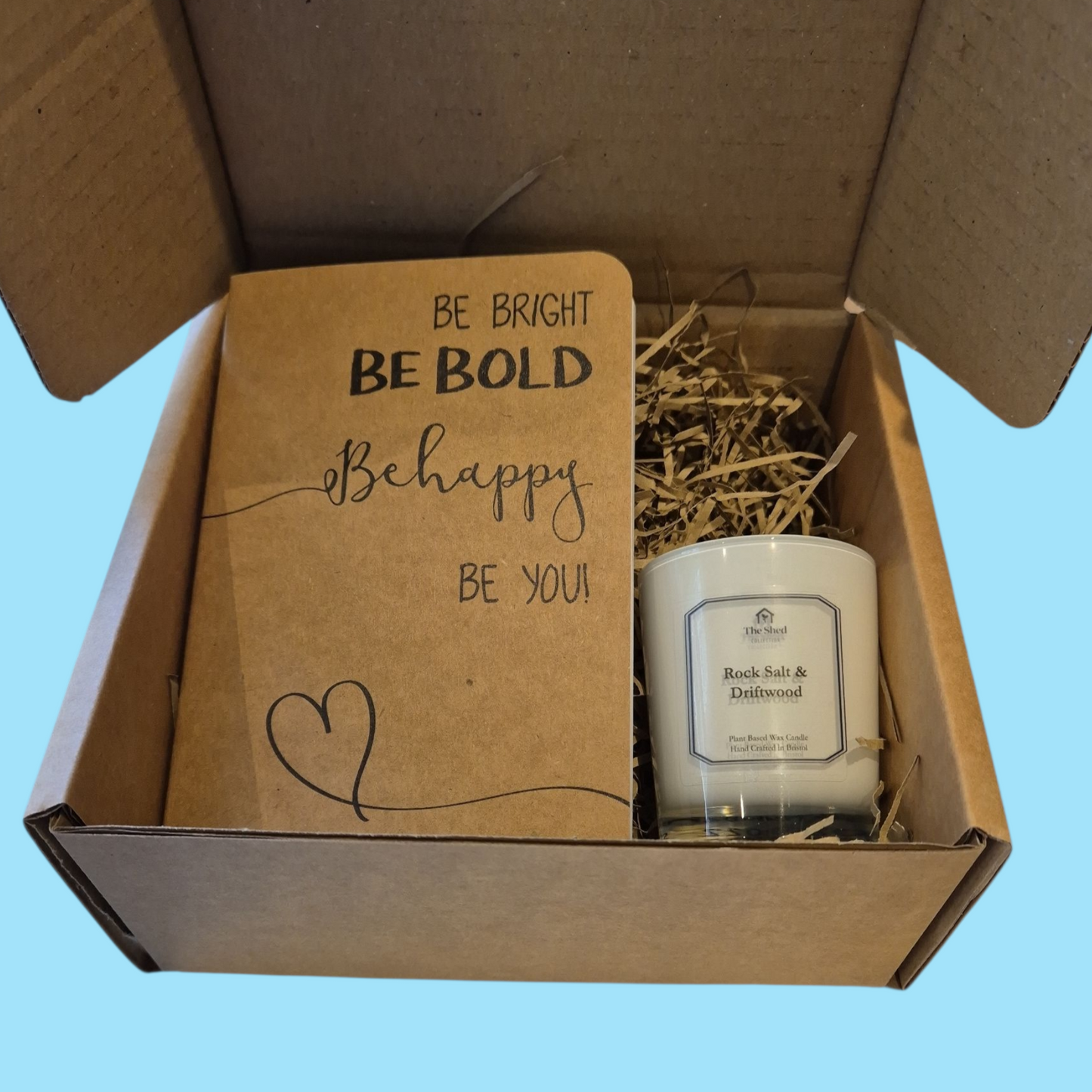 Box with a notebook and candle on a blue background