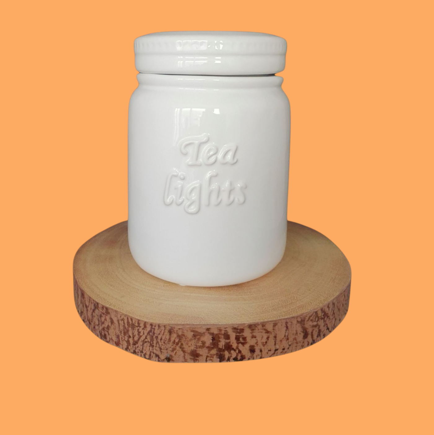 A white ceramic storage jar with 'Tea Lights' text on it, placed on a wooden round tray, against an orange background.