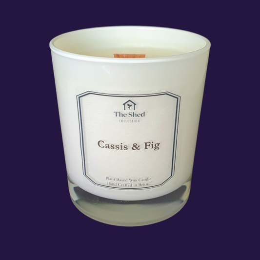 Picture shows a vegan friendly Cassis & Fig candle from The Shed Collection candle in a white container against a purple background.